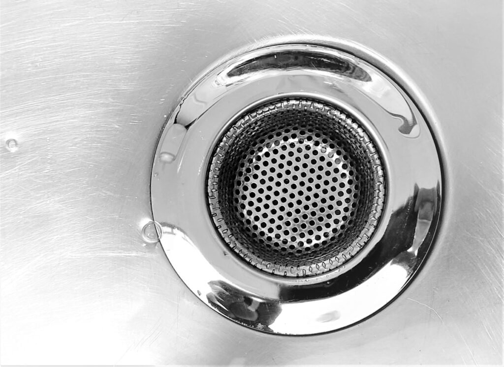 Close-up of a stainless steel sink drain showing pipe inspection focus after Texas winter